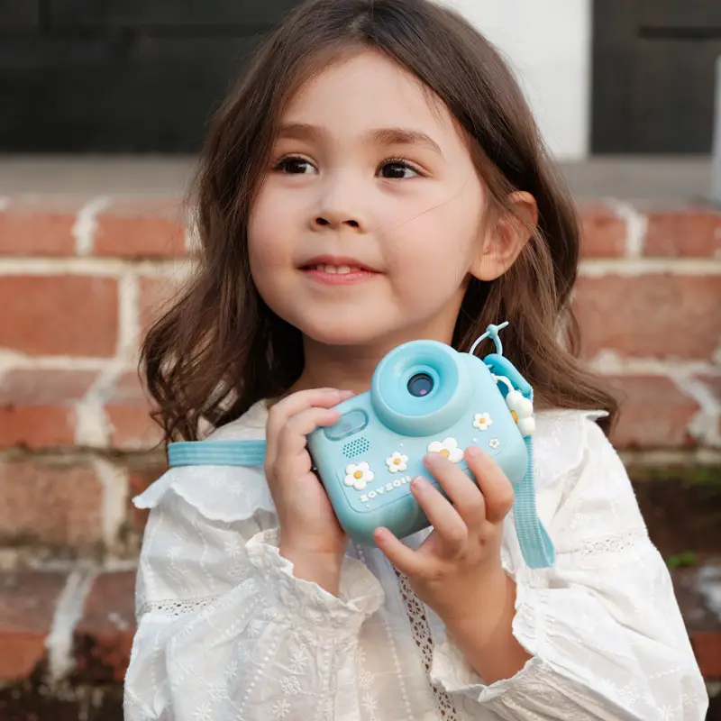 Uśmiechnięta dziewczynka trzymająca w dłoniach niebieski aparat fotograficzny Zoy Zoii na spacerze