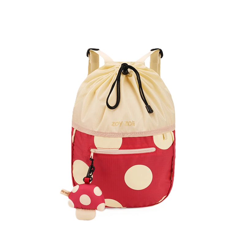 Czerwony plecak dziecięcy Zoy Zoii w duże kremowe grochy z kremową górą, złotym napisem i odpinanym brelokiem w kształcie muchomora.